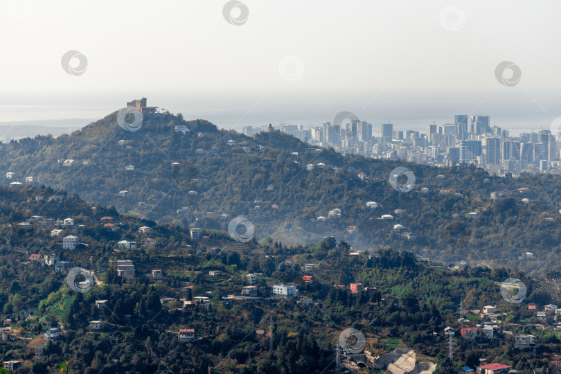 Скачать Сельская местность в Грузии. Сельские дома, расположенные на склонах гор. На заднем плане - небоскребы Батуми. фотосток Ozero