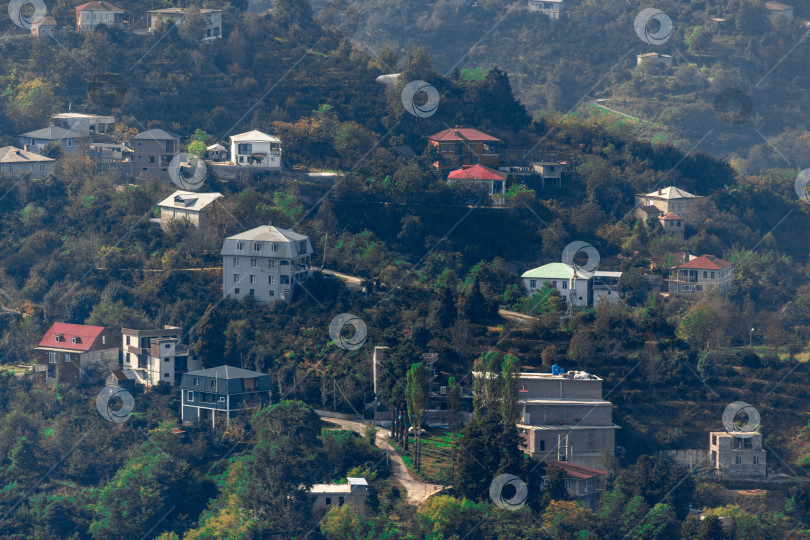 Скачать Сельская местность в Батуми. Сельские дома расположены на склонах гор. Одноэтажные, двухэтажные и трехэтажные дома окружены высокими зелеными деревьями. фотосток Ozero