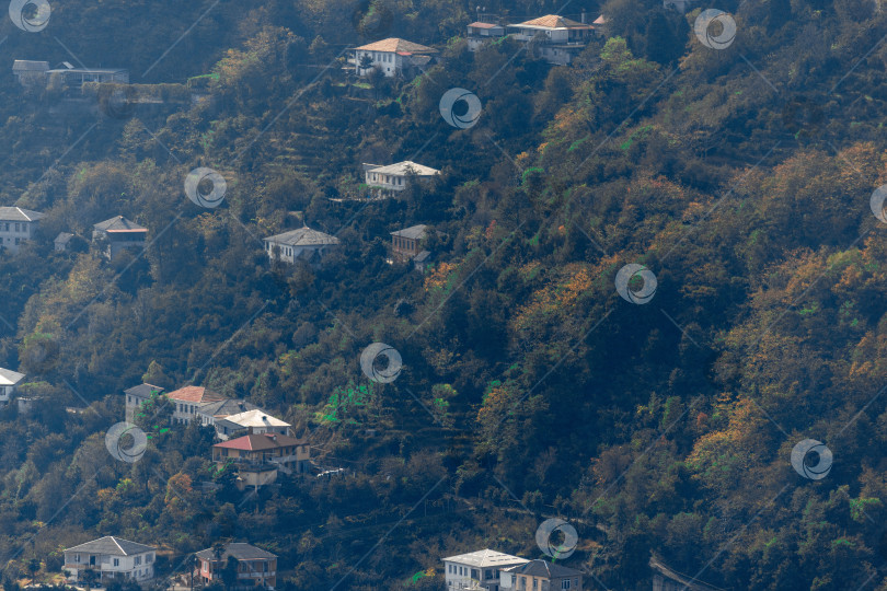 Скачать Сельская местность в Батуми. Сельские дома расположены на склонах гор. Одноэтажные, двухэтажные и трехэтажные дома окружены высокими зелеными деревьями. фотосток Ozero