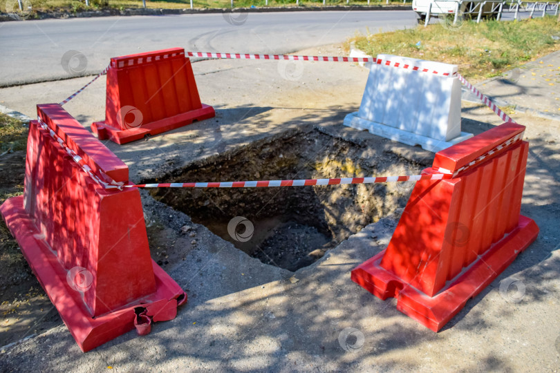 Скачать Коммунальная яма на дороге окружена сигнальной лентой и бордюрами фотосток Ozero