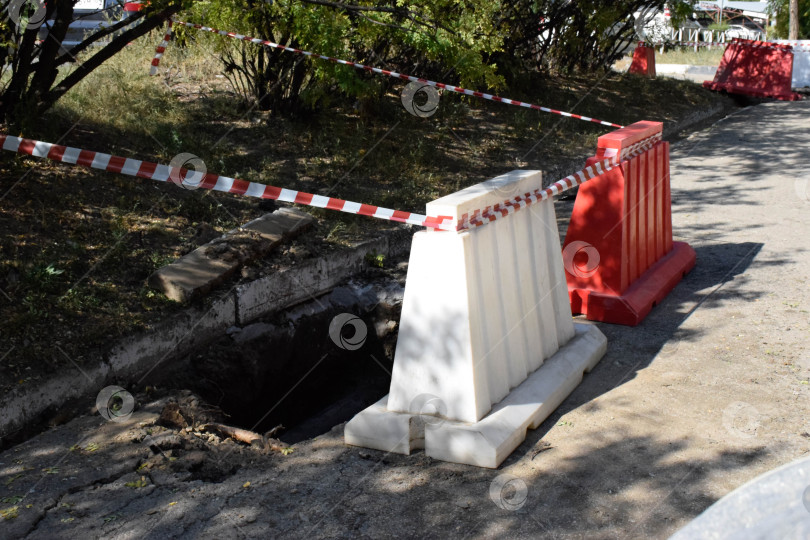 Скачать Яма на тротуаре обнесена красными бордюрами фотосток Ozero