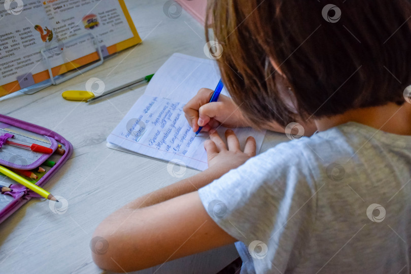 Скачать Ребенок делает домашнее задание по русскому языку сидя дома за столом фотосток Ozero