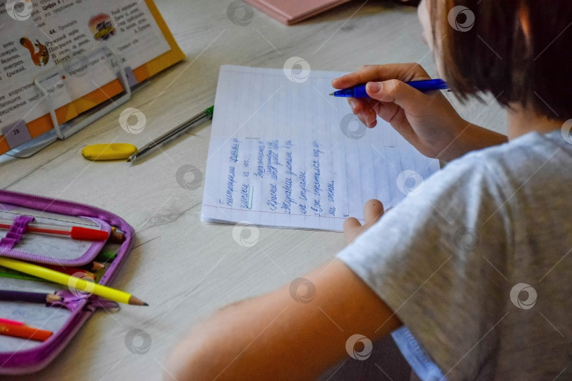 Скачать Ребенок внимательно записывает текст из учебника фотосток Ozero