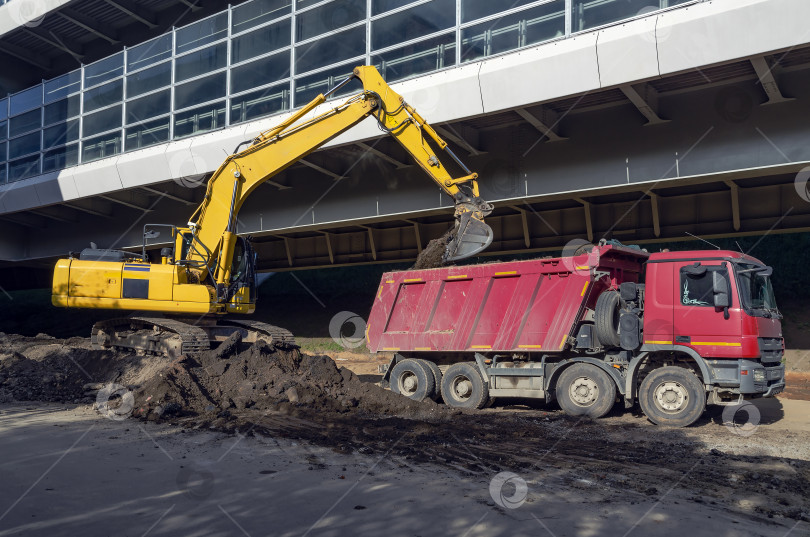 Скачать Экскаватор загружает грунт в кузов самосвала фотосток Ozero
