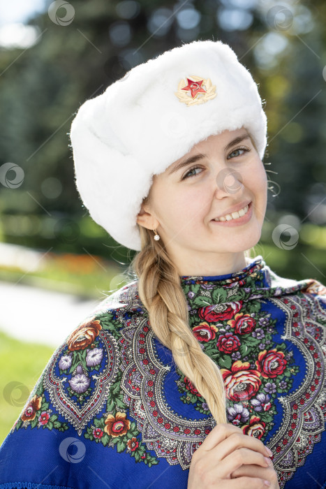Скачать Портрет красивой молодой славянской девушки в белой меховой шапке-ушанке. фотосток Ozero