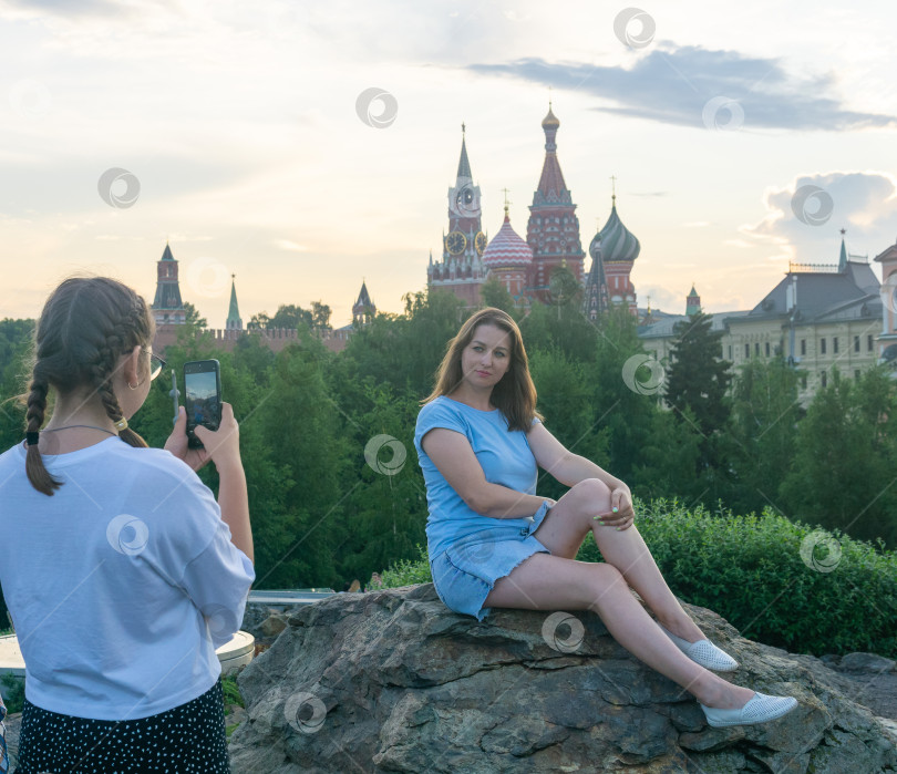 Скачать Две молодые женщины фотографируются в парке Зарядье на фоне Московского Кремля. фотосток Ozero