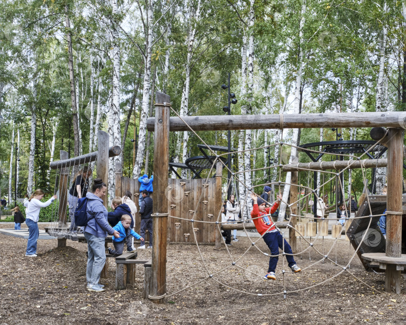 Скачать Дети и родители наслаждаются деревянной игровой площадкой в городском парке фотосток Ozero
