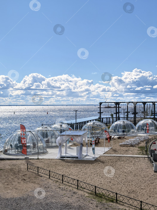 Скачать Санкт-Петербург, Россия - 20.08.2025. Кафе с ветрозащитными куполами над столиками на берегу Финского залива. фотосток Ozero
