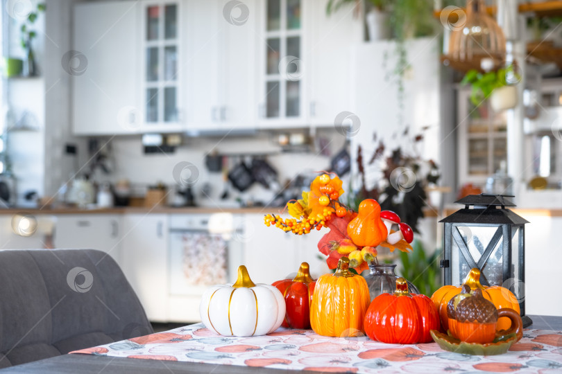 Скачать Декор белой классической кухни с тыквами, гирляндами, осенним букетом из желтых листьев к Хэллоуину и сбору урожая. Осеннее настроение в домашнем интерьере, современный стиль лофт. недвижимость, страхование, ипотека фотосток Ozero