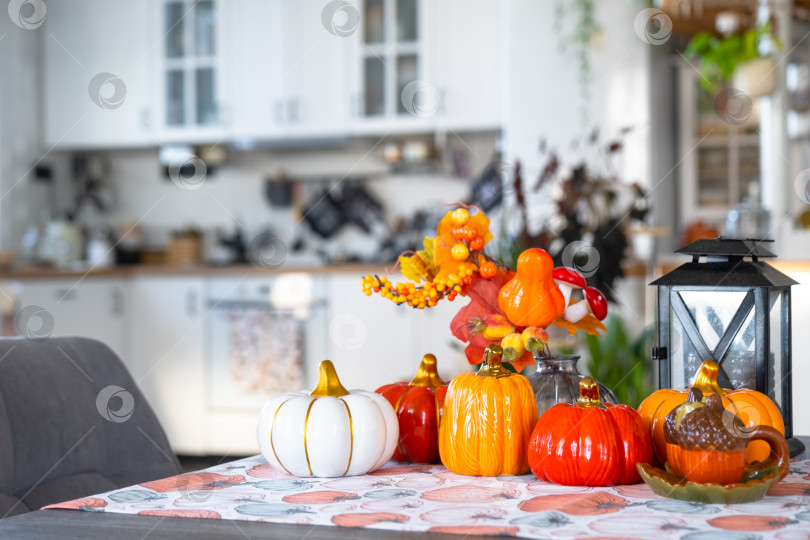 Скачать Декор белой классической кухни с тыквами, гирляндами, осенним букетом из желтых листьев к Хэллоуину и сбору урожая. Осеннее настроение в домашнем интерьере, современный стиль лофт. недвижимость, страхование, ипотека фотосток Ozero