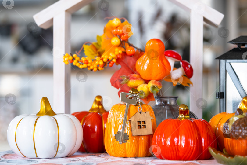 Скачать Уютный осенний декор на белой кухне с крошечным домиком и ключами, тыквами, осенними листьями, осенним настроением, Хэллоуином, праздником урожая, жильем, переездом, ипотекой, страховкой. фотосток Ozero