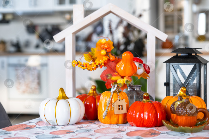 Скачать Уютный осенний декор на белой кухне с крошечным домиком и ключами, тыквами, осенними листьями, осенним настроением, Хэллоуином, праздником урожая, жильем, переездом, ипотекой, страховкой. фотосток Ozero