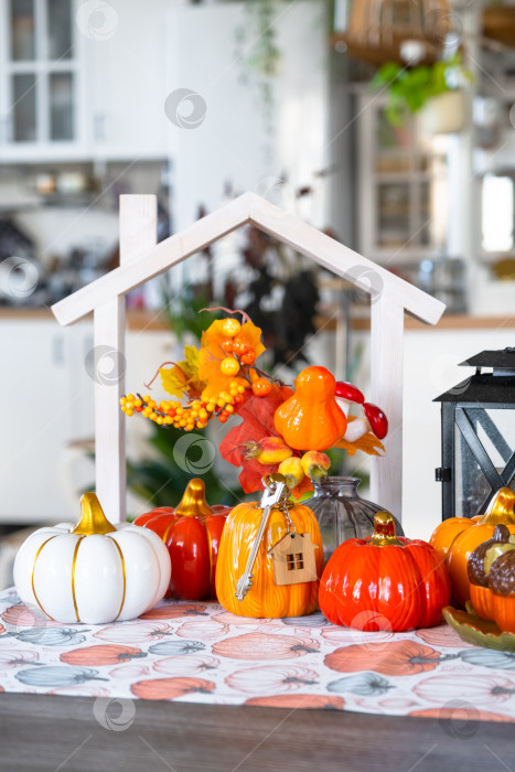 Скачать Уютный осенний декор на белой кухне с крошечным домиком и ключами, тыквами, осенними листьями, осенним настроением, Хэллоуином, праздником урожая, жильем, переездом, ипотекой, страховкой. фотосток Ozero