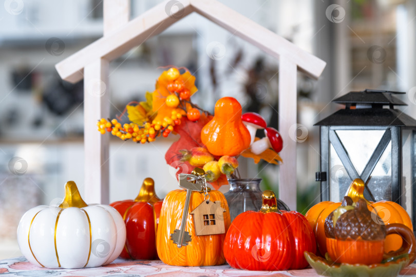 Скачать Уютный осенний декор на белой кухне с крошечным домиком и ключами, тыквами, осенними листьями, осенним настроением, Хэллоуином, праздником урожая, жильем, переездом, ипотекой, страховкой. фотосток Ozero