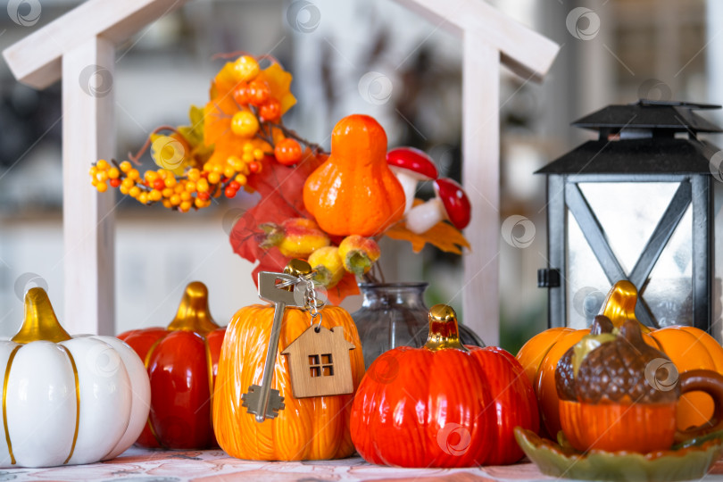 Скачать Уютный осенний декор на белой кухне с крошечным домиком и ключами, тыквами, осенними листьями, осенним настроением, Хэллоуином, праздником урожая, жильем, переездом, ипотекой, страховкой. фотосток Ozero