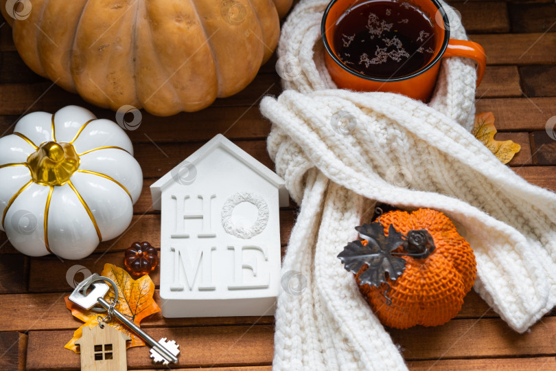 Скачать Уютный макет на деревянном фоне из реек с тыквами, осенними листьями, крошечным домиком и ключами - осеннее настроение, Хэллоуин, жилье, переезд, ипотека, страховка. фотосток Ozero