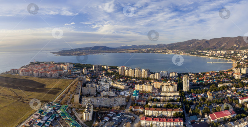 Скачать Панорама города Геленджика. На переднем плане жилые кварталы. Геленджикская бухта с гладкой голубой водой, Кавказские горы на заднем плане. Солнечная погода фотосток Ozero