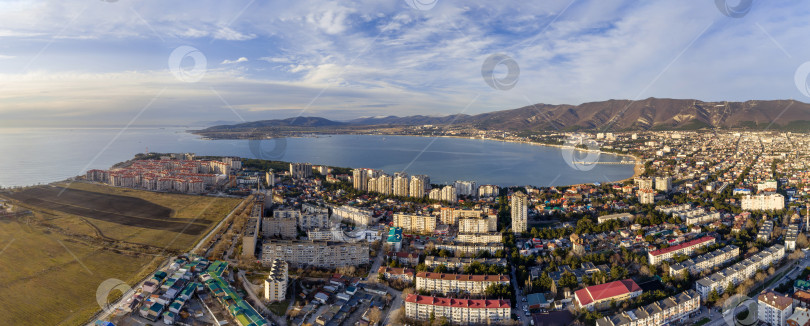 Скачать Панорама города Геленджика. На переднем плане жилые кварталы. Геленджикская бухта с гладкой голубой водой, Кавказские горы на заднем плане. Солнечная погода фотосток Ozero