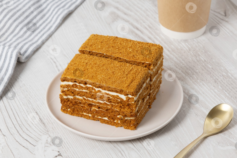 Скачать Вкусный слоеный медовый пирог, подаваемый на простой тарелке с теплым напитком рядом, идеально подходит для послеобеденного угощения фотосток Ozero
