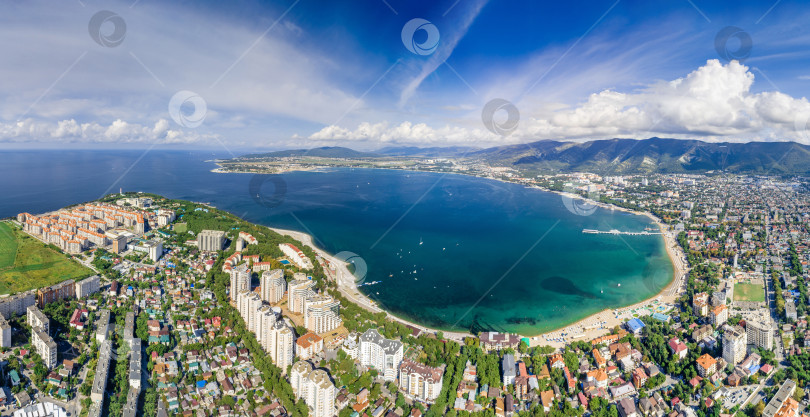 Скачать Панорама Геленджика с воздуха. Геленджикская бухта с голубой водой. Пляж вдоль берега бухты. Яхты на воде. Жилые дома вокруг бухты. Кавказские горы в белых облаках. фотосток Ozero