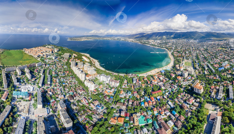 Скачать Панорама Геленджика с воздуха. Геленджикская бухта с голубой водой. Пляж вдоль берега бухты. Яхты на воде. Жилые дома вокруг бухты. Кавказские горы в белых облаках. фотосток Ozero