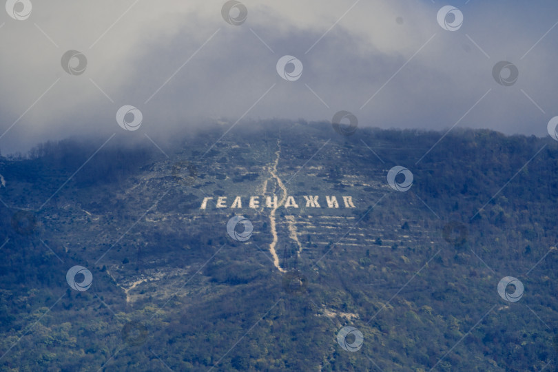 Скачать Надпись "Геленджик" на склоне хребта Маркотх. Вершина Кавказских гор в облаках. Курорт Геленджик фотосток Ozero