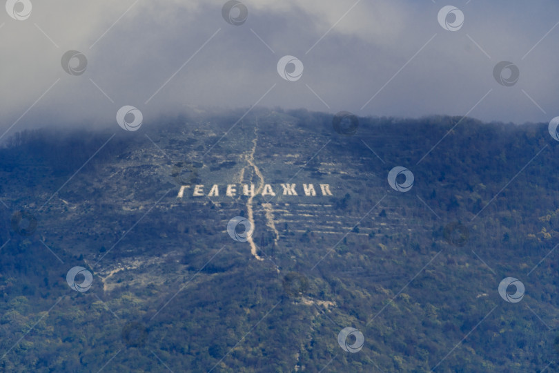 Скачать Надпись "Геленджик" на склоне хребта Маркотх. Вершина Кавказских гор в облаках. Курорт Геленджик фотосток Ozero