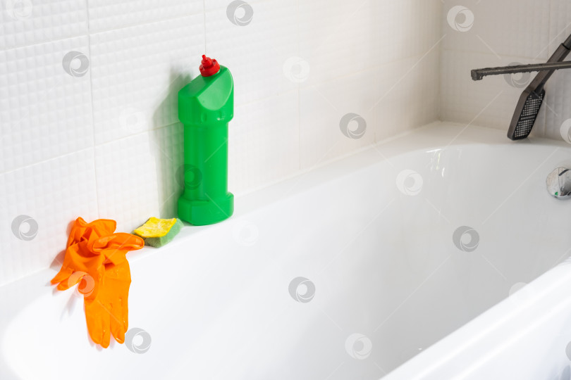 Скачать Крупным планом бутылка с моющим средством в ванной комнате дома, губка для мытья посуды и резиновые перчатки в ванной. Наведение порядка, чистоты и гигиены в доме, услуги по уборке фотосток Ozero
