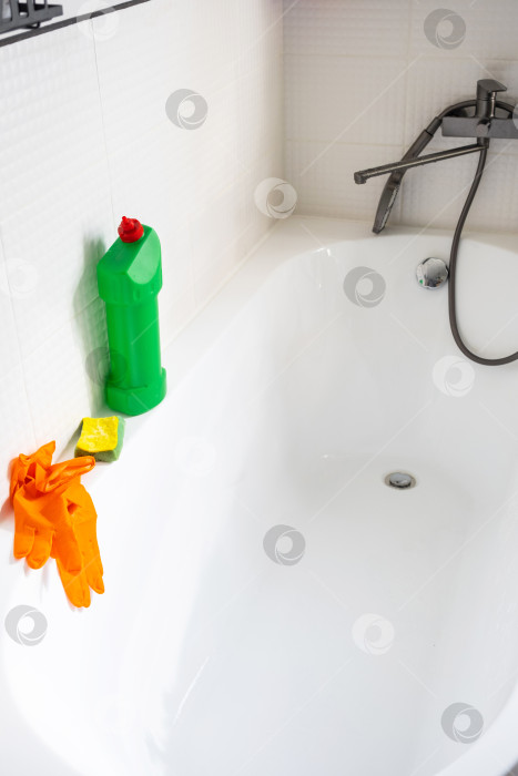 Скачать Крупным планом бутылка с моющим средством в ванной комнате дома, губка для мытья посуды и резиновые перчатки на ванной. Наведение порядка, чистоты и гигиены в доме, услуги по уборке фотосток Ozero
