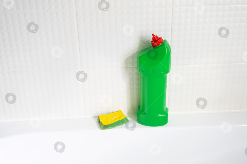 Скачать Крупным планом бутылка с моющим средством в ванной комнате дома, губка для мытья посуды и резиновые перчатки в ванной. Наведение порядка, чистоты и гигиены в доме, услуги по уборке фотосток Ozero