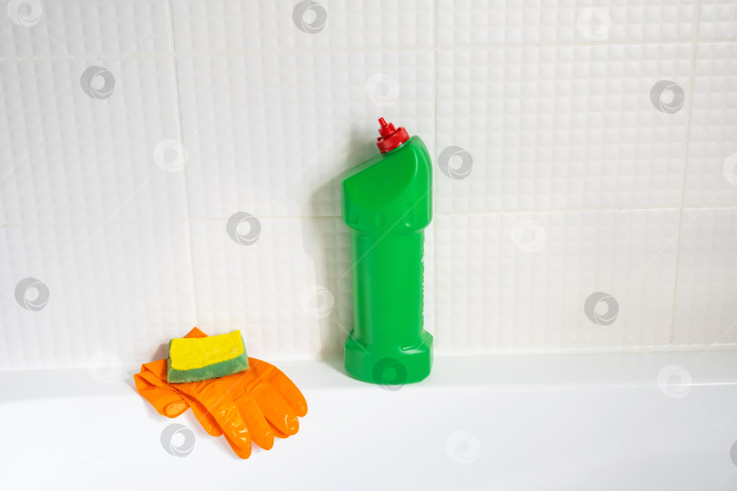Скачать Крупным планом бутылка с моющим средством в ванной комнате дома, губка для мытья посуды и резиновые перчатки в ванной. Наведение порядка, чистоты и гигиены в доме, услуги по уборке фотосток Ozero