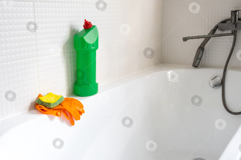 Скачать Крупным планом бутылка с моющим средством в ванной комнате дома, губка для мытья посуды и резиновые перчатки в ванной. Наведение порядка, чистоты и гигиены в доме, услуги по уборке фотосток Ozero