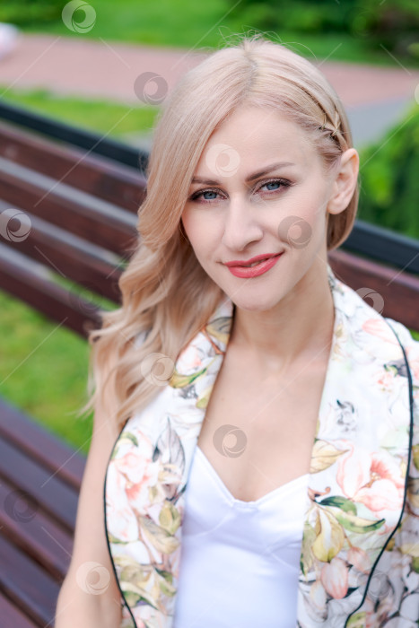 Скачать Женщина со светлыми волосами и шарфом в цветочек сидит на скамейке фотосток Ozero