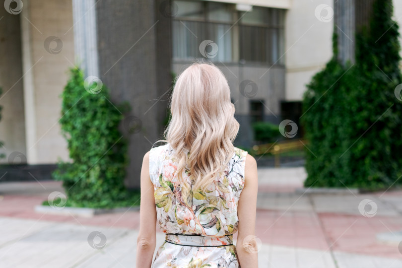 Скачать Женщина со светлыми волосами и в платье в цветочек стоит перед зданием фотосток Ozero