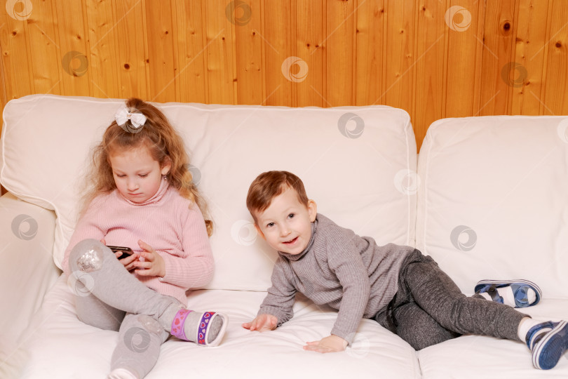 Скачать Мальчик и девочка сидят на диване фотосток Ozero