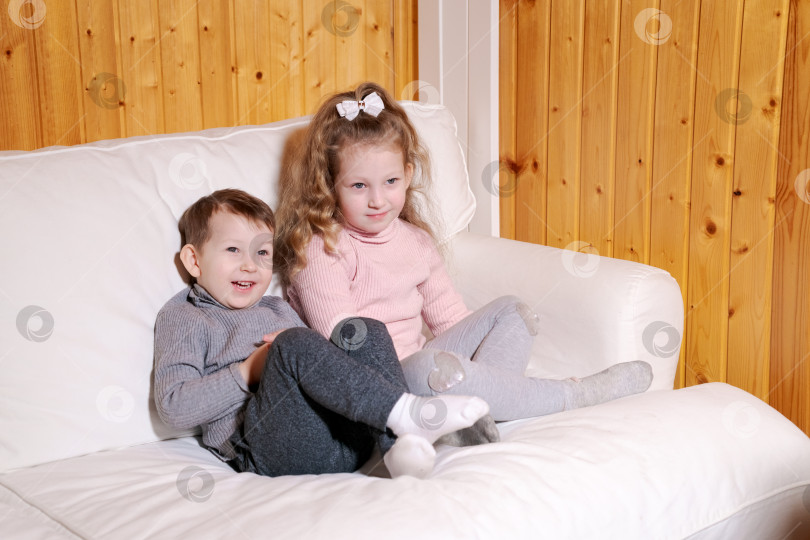 Скачать Мальчик и девочка сидят на белом диване фотосток Ozero