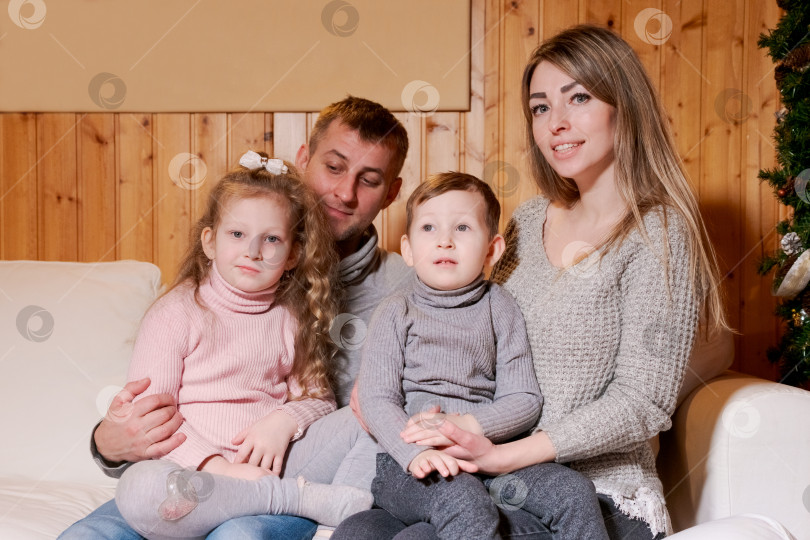 Скачать Семья из четырех человек сидит на диване фотосток Ozero