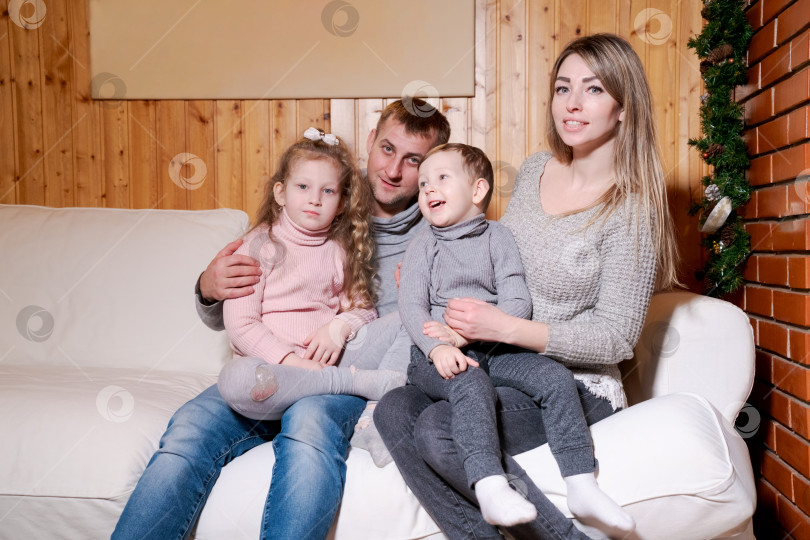 Скачать Семья из четырех человек сидит на диване фотосток Ozero