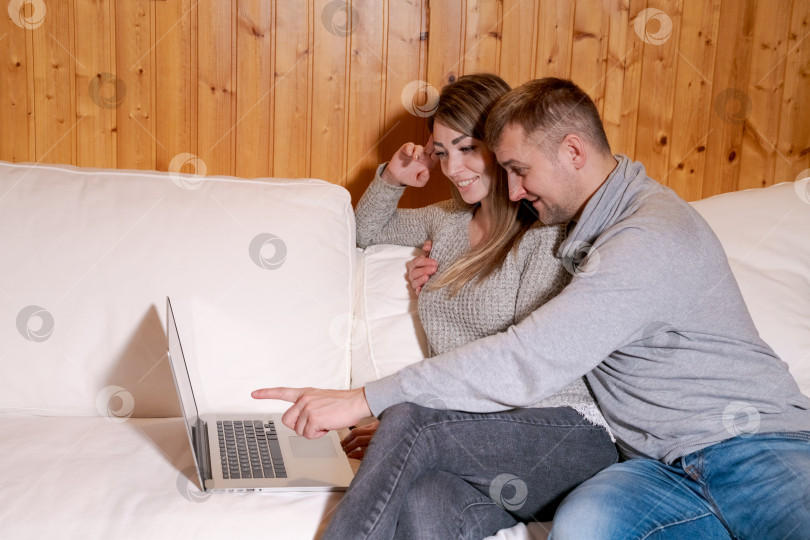 Скачать Мужчина и женщина сидят на диване и смотрят в ноутбук фотосток Ozero