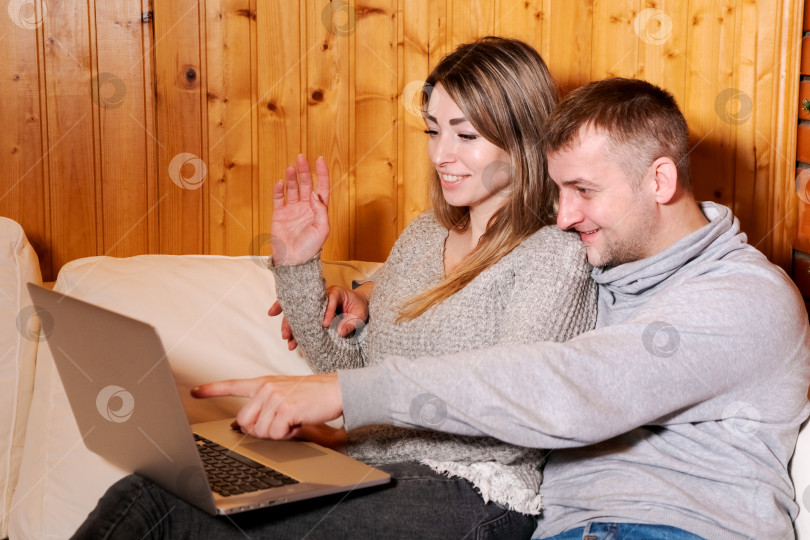 Скачать Мужчина и женщина сидят на диване и смотрят в ноутбук фотосток Ozero