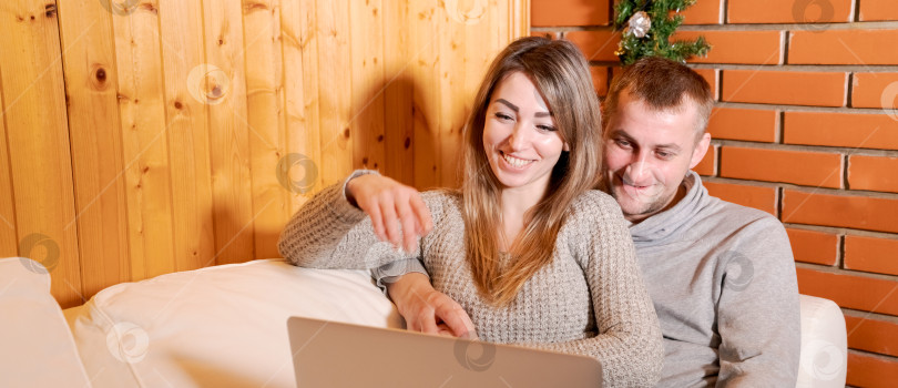Скачать Мужчина и женщина сидят на диване и смотрят в ноутбук фотосток Ozero