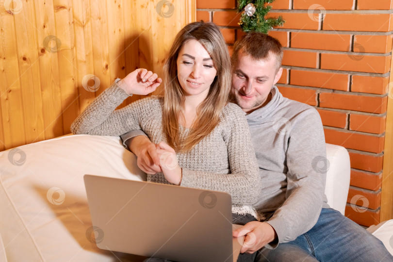 Скачать Мужчина и женщина сидят на диване и смотрят в ноутбук фотосток Ozero