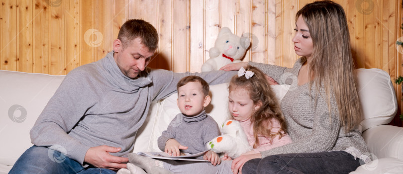 Скачать Мужчина и женщина сидят на диване с двумя детьми фотосток Ozero
