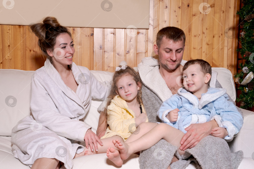Скачать Семья из четырех человек сидит на диване фотосток Ozero