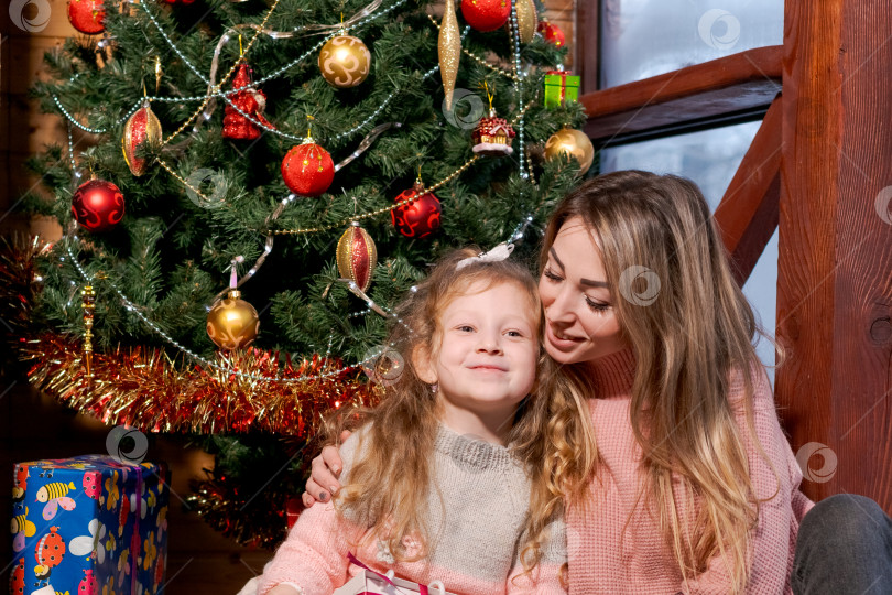 Скачать Женщина и маленькая девочка сидят вместе перед рождественской елкой фотосток Ozero