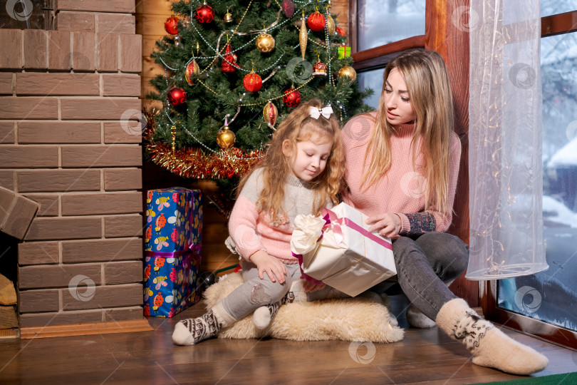 Скачать Женщина и ребенок сидят на коврике перед рождественской елкой фотосток Ozero