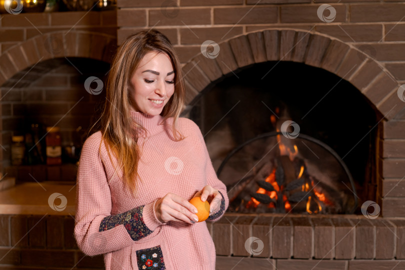 Скачать Женщина держит апельсин перед камином фотосток Ozero