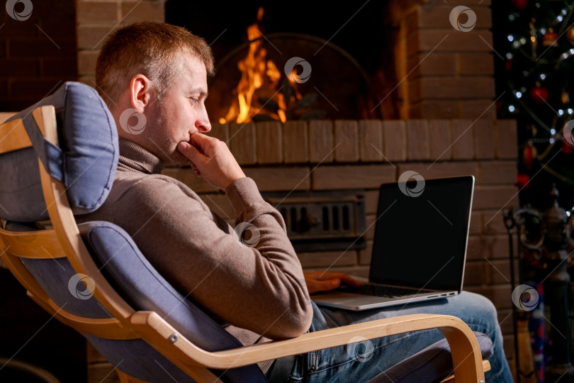 Скачать Мужчина сидит в кресле с ноутбуком перед собой фотосток Ozero