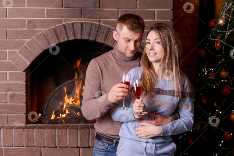 Скачать Мужчина и женщина с бокалами вина в руках стоят перед камином фотосток Ozero