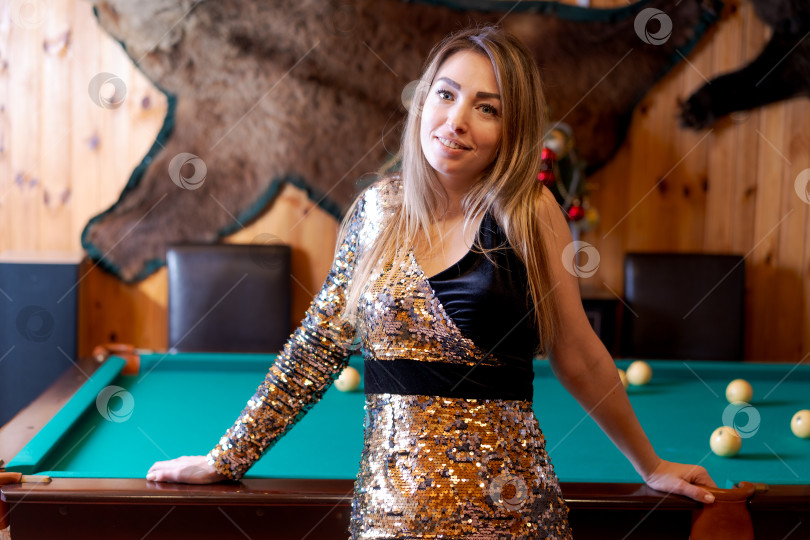 Скачать Женщина в черно-золотом платье стоит перед бильярдным столом фотосток Ozero